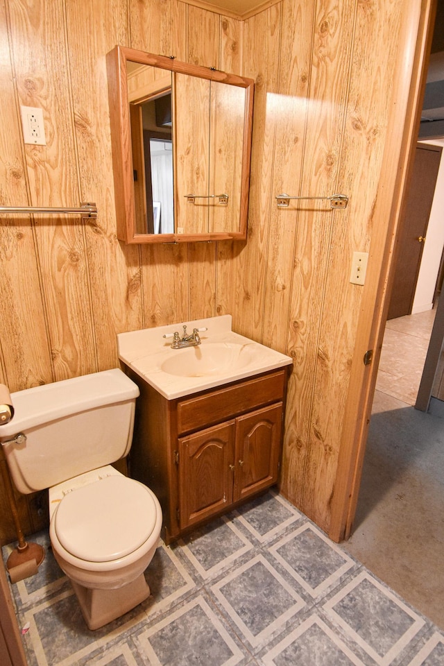 bathroom featuring vanity, toilet, and wood walls