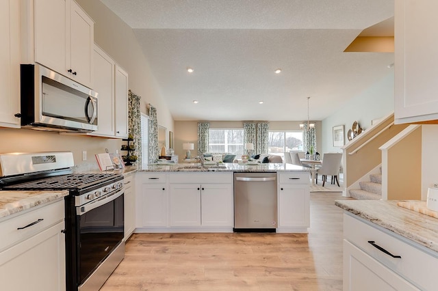 kitchen with kitchen peninsula, white cabinetry, vaulted ceiling, and appliances with stainless steel finishes