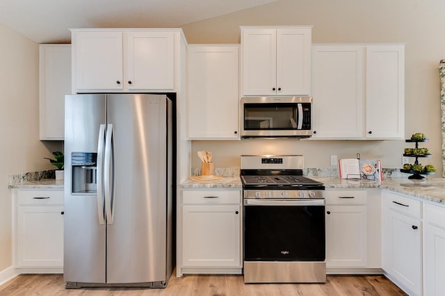 kitchen with white cabinets, appliances with stainless steel finishes, and light hardwood / wood-style flooring