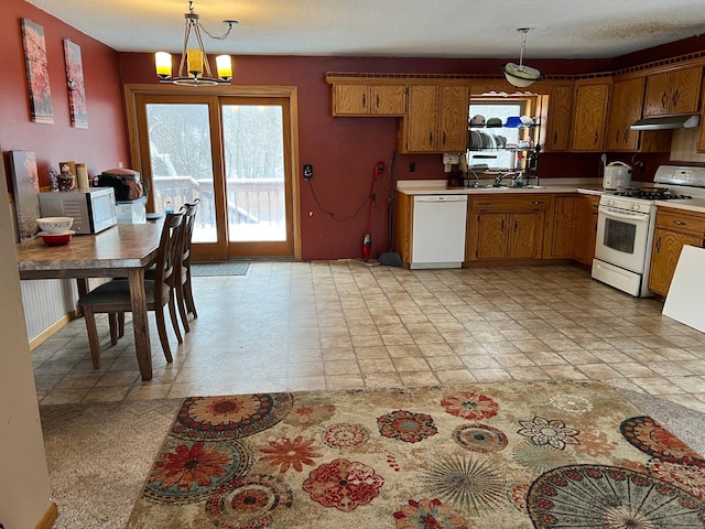 kitchen featuring white appliances, sink, exhaust hood, pendant lighting, and an inviting chandelier