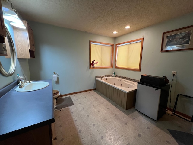 bathroom featuring a textured ceiling, vanity, toilet, and a tub to relax in