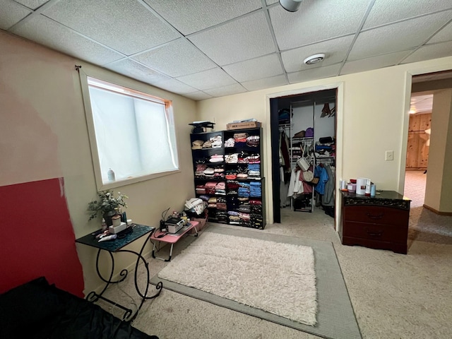 carpeted bedroom featuring a drop ceiling and a closet