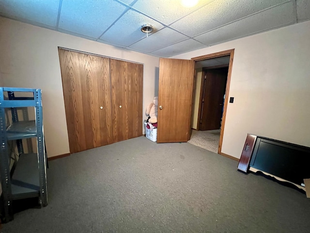 unfurnished bedroom featuring a drop ceiling, carpet floors, and a closet