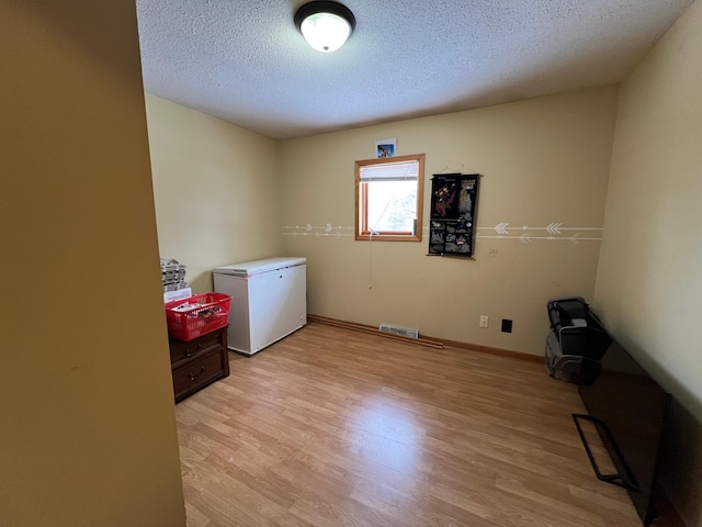 washroom with light hardwood / wood-style floors and a textured ceiling