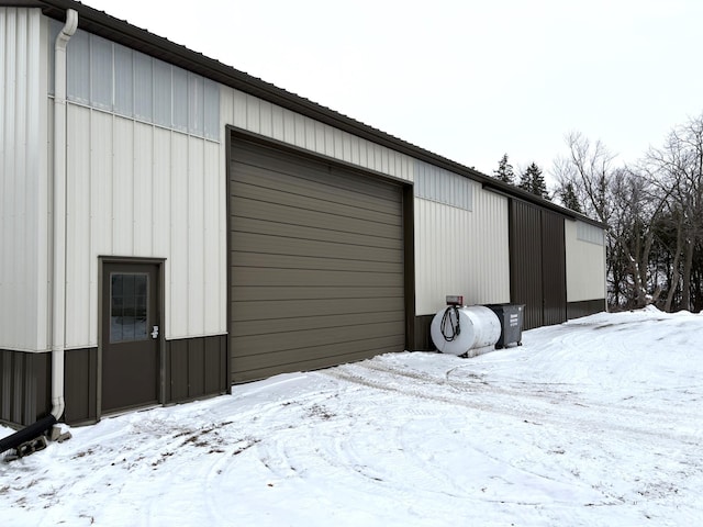 snow covered structure featuring a garage