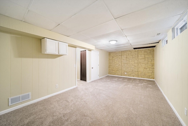 basement with a paneled ceiling and light colored carpet