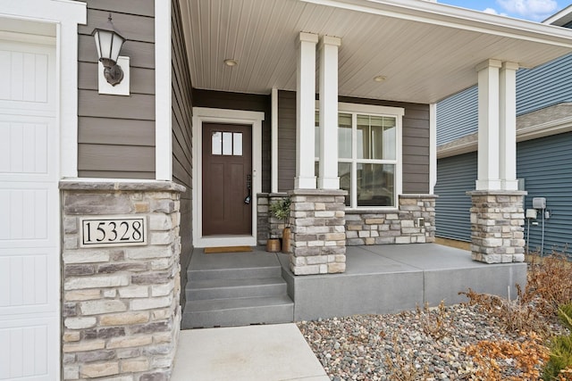 property entrance featuring a porch, an attached garage, and stone siding