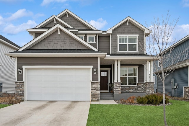 craftsman-style home with a front lawn, concrete driveway, covered porch, a garage, and stone siding