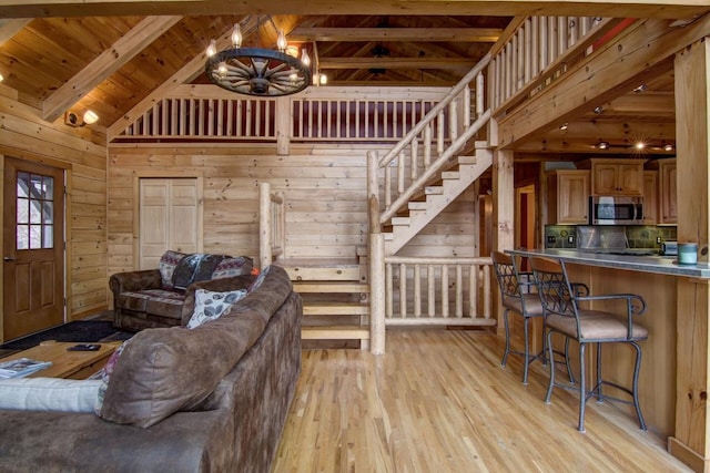 living room with wood walls, wooden ceiling, high vaulted ceiling, beamed ceiling, and light hardwood / wood-style floors