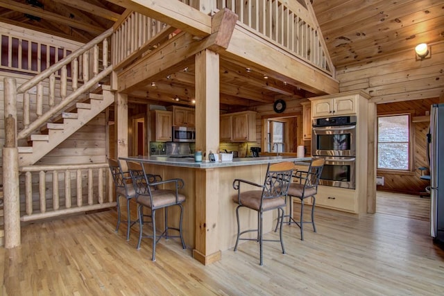 kitchen featuring kitchen peninsula, a kitchen bar, stainless steel appliances, and light hardwood / wood-style floors