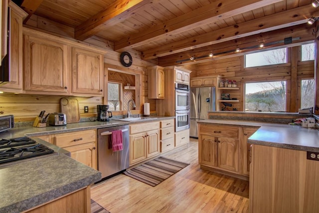 kitchen with sink, beamed ceiling, light hardwood / wood-style floors, wooden walls, and appliances with stainless steel finishes