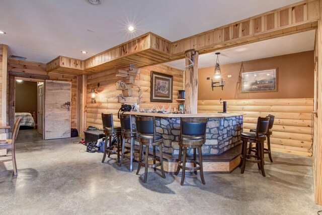 bar featuring decorative light fixtures, rustic walls, and concrete floors