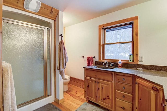 bathroom featuring vanity, hardwood / wood-style flooring, toilet, and a shower with shower door