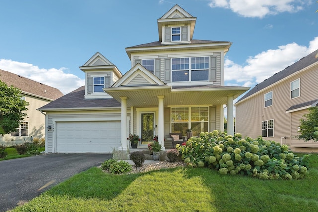 view of front of property featuring covered porch, a garage, and a front lawn