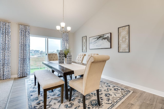 dining area with light wood-type flooring, an inviting chandelier, and lofted ceiling