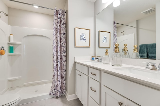 bathroom featuring tile patterned flooring, vanity, toilet, and walk in shower