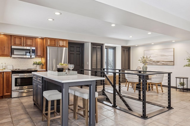 kitchen featuring a center island, appliances with stainless steel finishes, a kitchen breakfast bar, and decorative backsplash