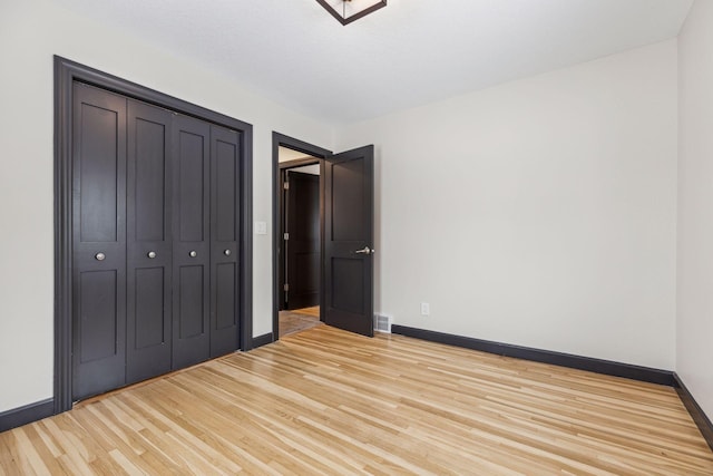 unfurnished bedroom with light hardwood / wood-style flooring and a closet