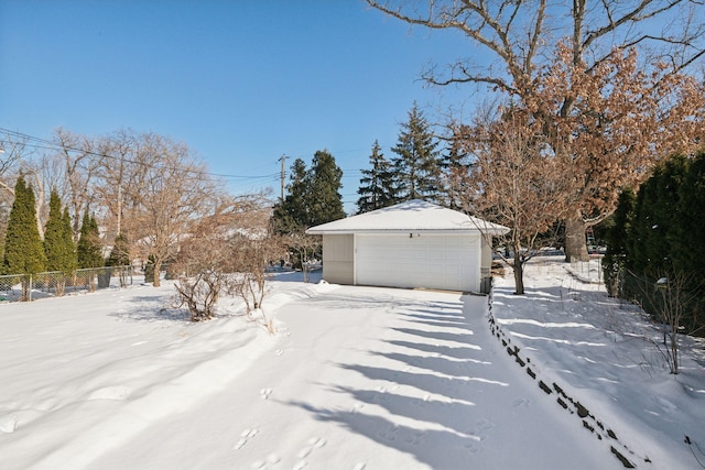 snowy yard with a garage and an outbuilding