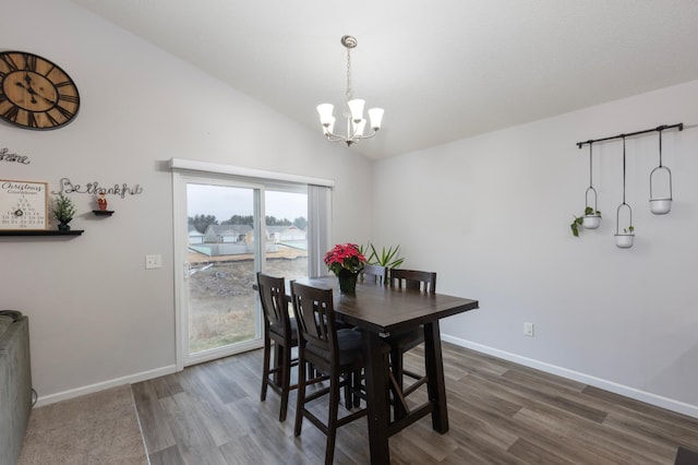 dining room featuring dark hardwood / wood-style flooring, an inviting chandelier, and vaulted ceiling