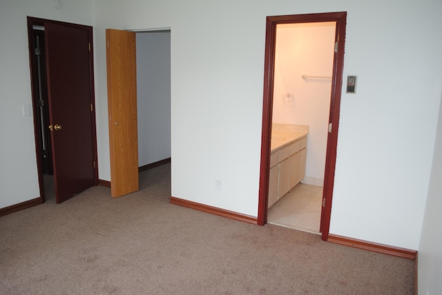 unfurnished bedroom featuring light colored carpet, connected bathroom, a closet, and a walk in closet