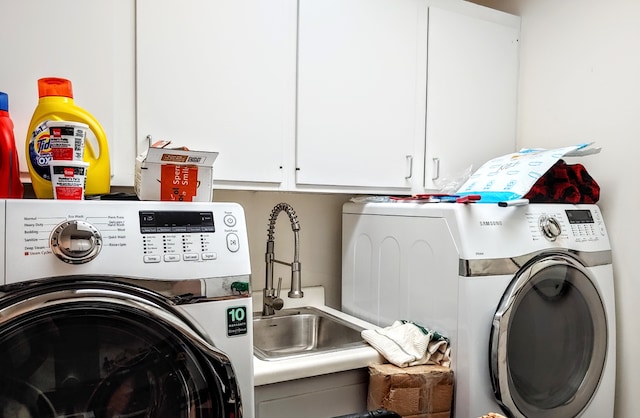 clothes washing area featuring separate washer and dryer, cabinets, and sink