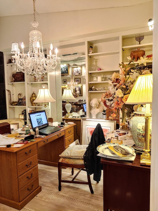 home office featuring vaulted ceiling, a chandelier, light wood-type flooring, and built in shelves