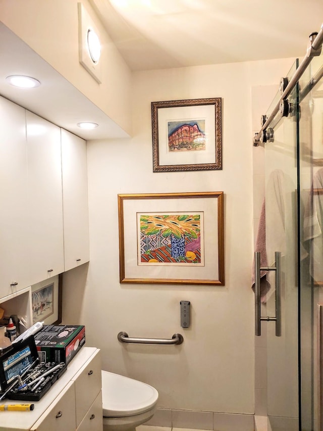 bathroom with toilet, tile patterned floors, and a shower with shower door