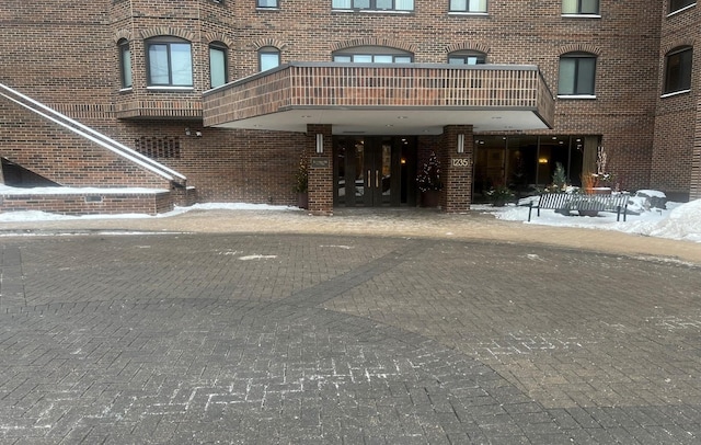 snow covered property entrance featuring a balcony