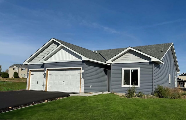 view of front of home featuring driveway, a shingled roof, a garage, and a front lawn