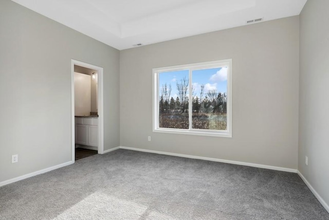 unfurnished bedroom featuring connected bathroom, visible vents, baseboards, carpet, and a raised ceiling