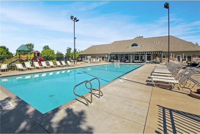 community pool with playground community, a patio, and fence