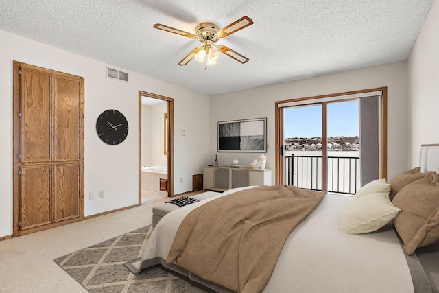 carpeted bedroom featuring ceiling fan, access to exterior, a textured ceiling, and ensuite bath