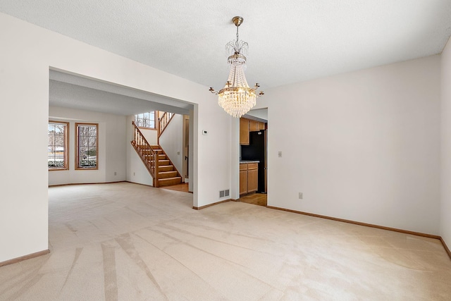 carpeted empty room featuring a chandelier