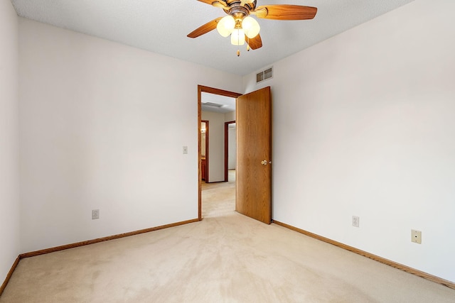 empty room featuring ceiling fan and light carpet