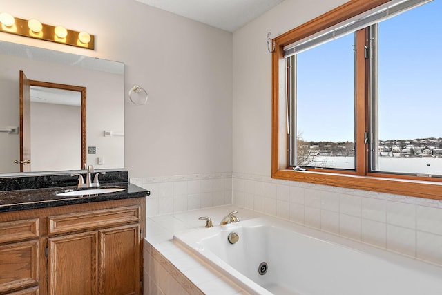 bathroom featuring tiled tub and vanity