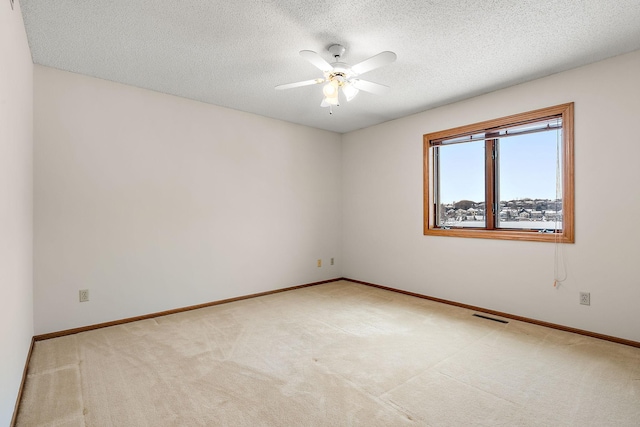 carpeted spare room featuring ceiling fan and a textured ceiling