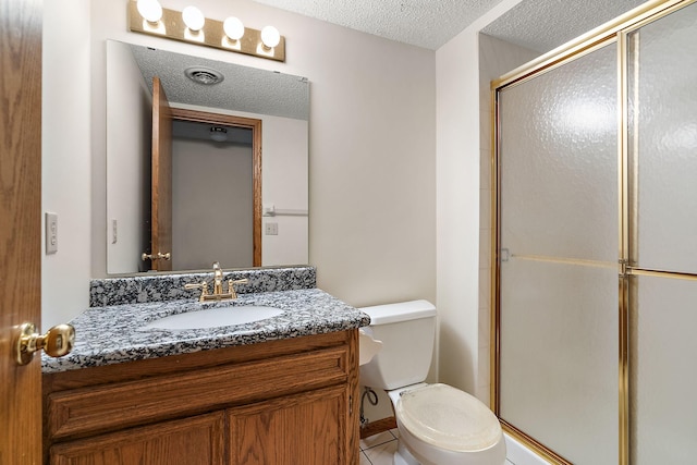 bathroom featuring toilet, vanity, tile patterned floors, a textured ceiling, and a shower with door