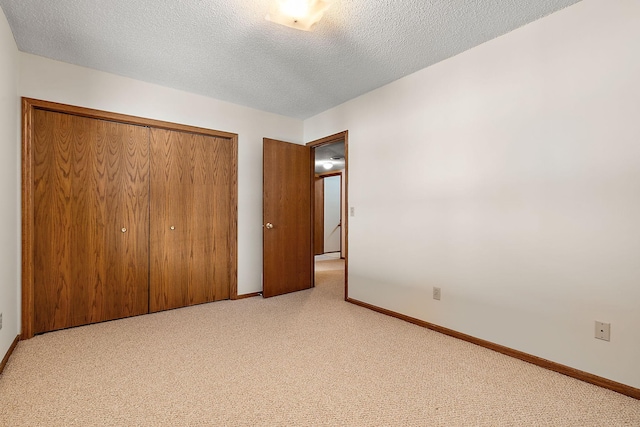 unfurnished bedroom with light carpet, a closet, and a textured ceiling