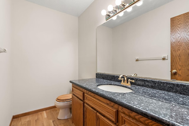 bathroom with toilet, a textured ceiling, hardwood / wood-style floors, and vanity