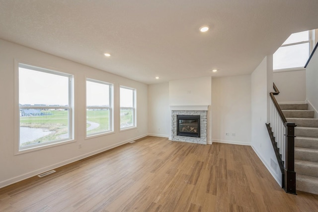 unfurnished living room with a fireplace, a textured ceiling, and light hardwood / wood-style floors