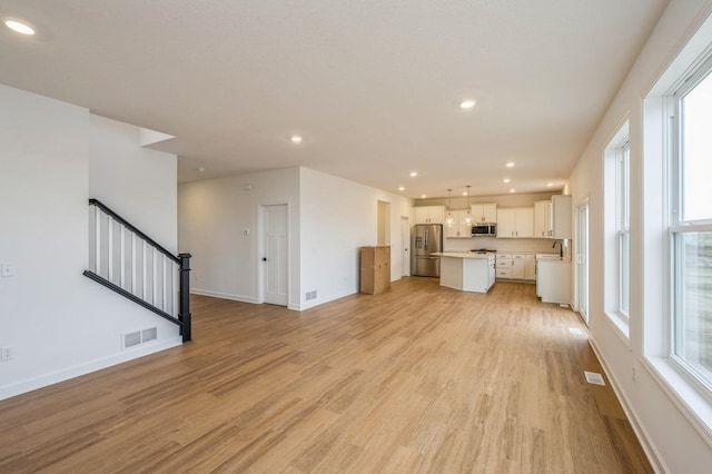 unfurnished living room with sink and light wood-type flooring