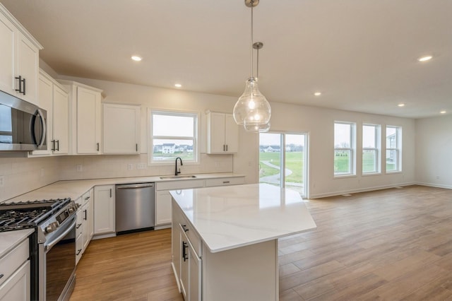 kitchen featuring white cabinets, light hardwood / wood-style floors, a kitchen island, and stainless steel appliances