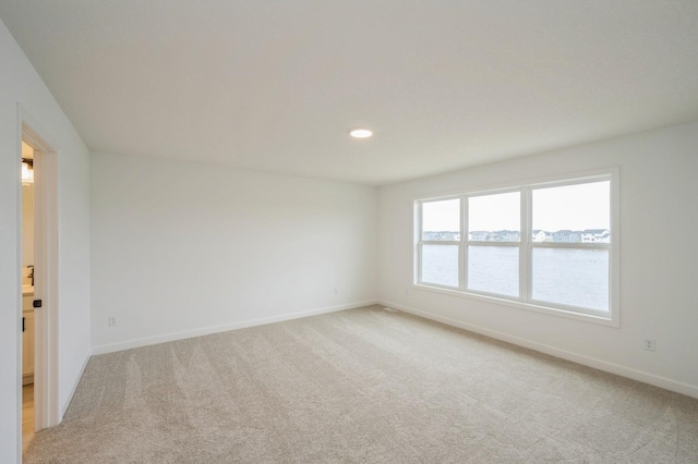 carpeted spare room featuring a water view