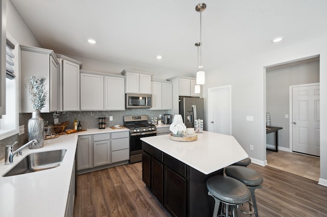 kitchen with pendant lighting, dark hardwood / wood-style flooring, stainless steel appliances, and sink