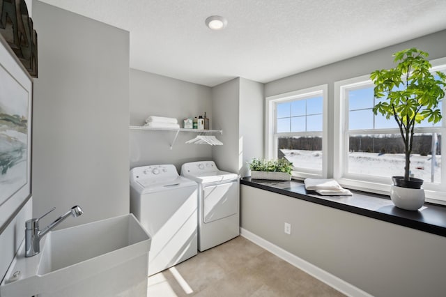 clothes washing area with independent washer and dryer, a textured ceiling, and sink