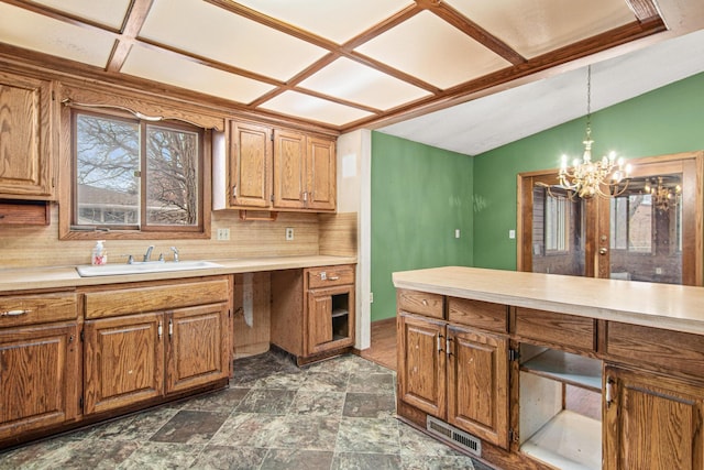 kitchen featuring pendant lighting, lofted ceiling, sink, decorative backsplash, and a notable chandelier