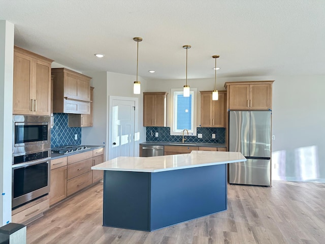 kitchen with built in appliances, a center island, light hardwood / wood-style floors, and sink