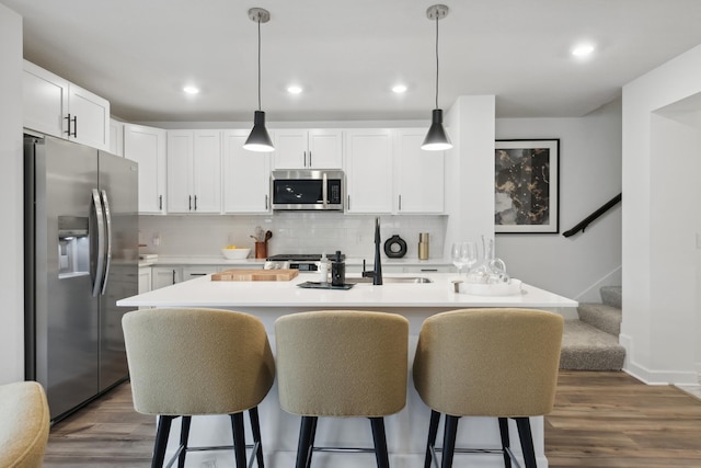 kitchen featuring white cabinets, decorative light fixtures, and appliances with stainless steel finishes