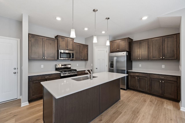 kitchen featuring sink, appliances with stainless steel finishes, dark brown cabinetry, a center island with sink, and decorative light fixtures